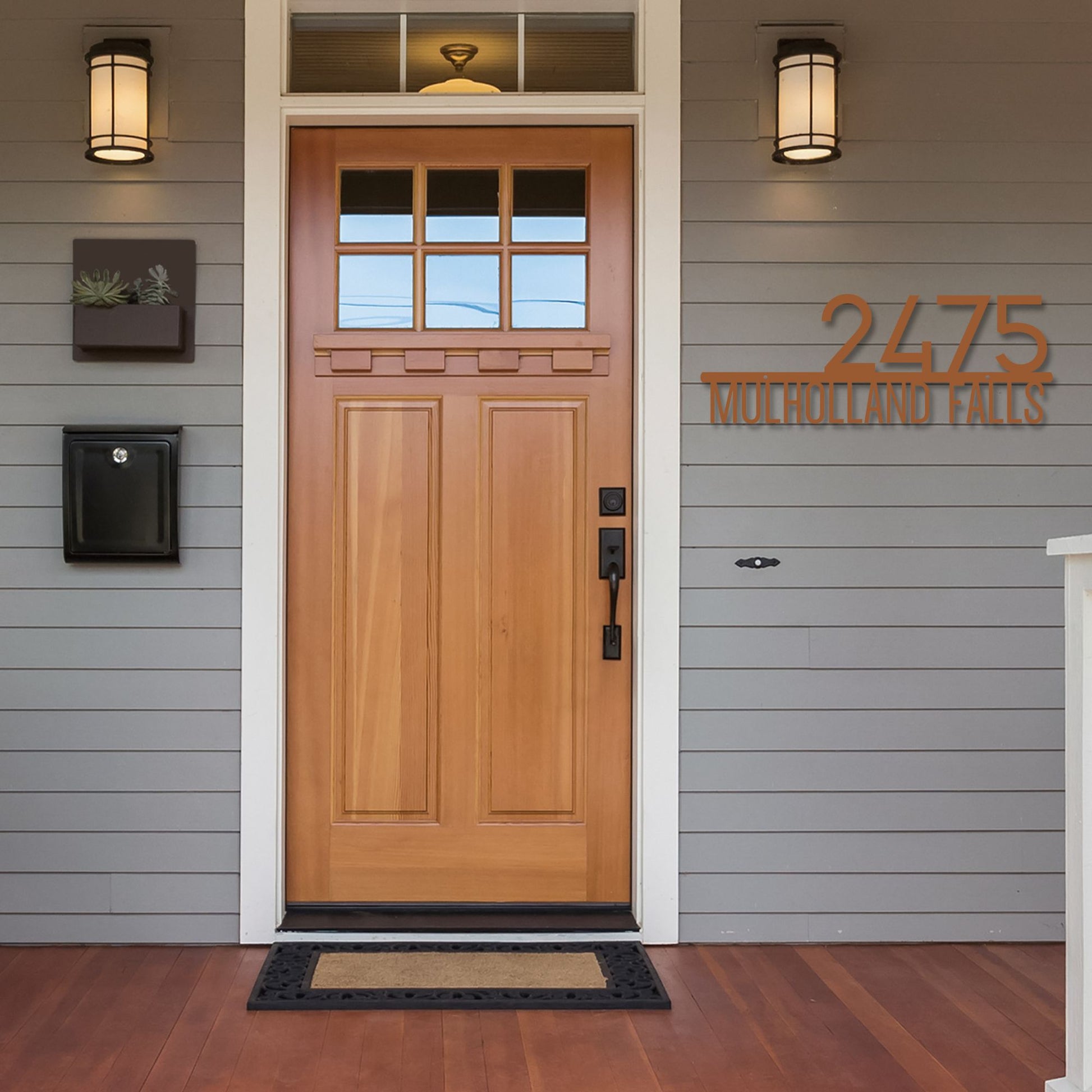 Wooden front door with address numbers '2475' on a gray house exterior.
